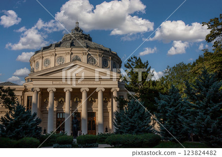 Visitors admire the exquisite architecture of Romanian Athenaeum in Bucharest on a clear blue sky afternoon surrounded by a serene atmosphere 123824482