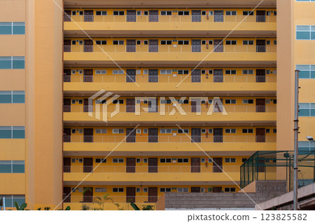 Symmetrical facade of a modern apartment building with repeating balconies and doors 123825582