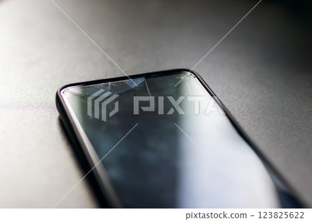 A mobile phone that has a broken screen is currently sitting on a table 123825622