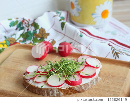Slice of sourdough bread with fresh radish on the cutting board. 123826149