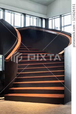 Layered wood spiral staircase with railings handle grip interior of Bank of Thailand Learning Center. 123826351