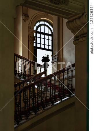Vintage staircase railing or stairway banister leading into hallway on the 2nd floor with open casement window. 123826354