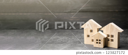 Miniature wooden houses on black background. Affordable housing. Search purchase best option apartment and real estate, rent. Copy space, banner Miniature wooden houses on black background. Affordable housing. Search purchase best option apartment and real estate, rent. Copy space, banner 123827172