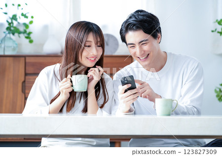 Smiling man and woman holding smartphones in the living room Smiling man and woman holding smartphones in the living room 123827309