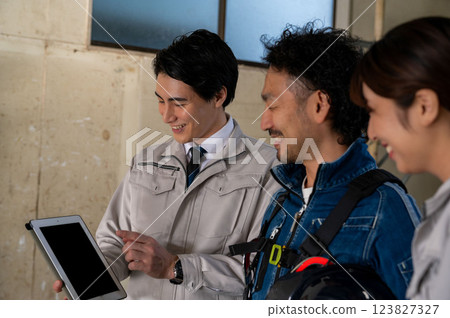 三個人，一男一女穿著工作服，正在看圖紙並開會 123827327
