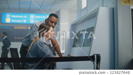 Two Security Officers Monitoring X-ray Images of Baggage Screening on Computer Screens Two Security Officers Monitoring X-ray Images of Baggage Screening on Computer Screens 123827648