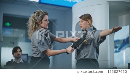 Female TSA Officer Demonstrating Process of Scanning with Metal Detector to Team of Workers Female TSA Officer Demonstrating Process of Scanning with Metal Detector to Team of Workers 123827650