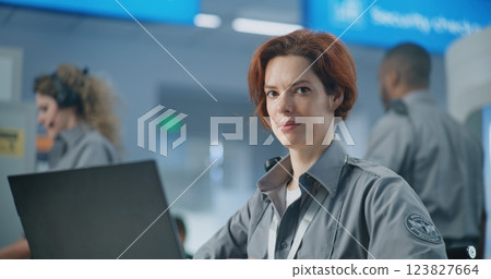 Airport Security Checkpoint: Serious Female Security Officer Using Laptop, Looking at Camera Airport Security Checkpoint: Serious Female Security Officer Using Laptop, Looking at Camera 123827664