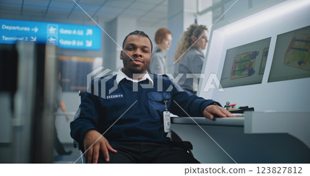 Portrait of TSA Worker Looking at Camera. Computer Screens Showing Baggage Scanning Procedure Portrait of TSA Worker Looking at Camera. Computer Screens Showing Baggage Scanning Procedure 123827812