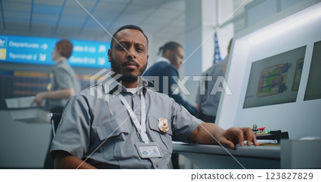 Portrait of TSA Worker Looking at Camera. Computer Screens Showing X-ray Images Portrait of TSA Worker Looking at Camera. Computer Screens Showing X-ray Images 123827829