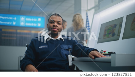 Portrait of TSA Worker Looking at Camera. Computer Screens Showing Baggage Scanning Procedure 123827831