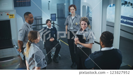 Female TSA Officer with Tablet Computer Instructs Group of Workers About Scanning Process 123827952