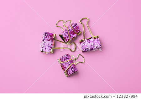 Gold paper clips with glitter on pink background 123827984
