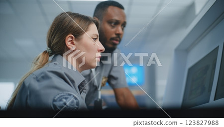Two Diverse TSA Workers Monitoring Baggage Screening Procedure on Computer Monitors 123827988