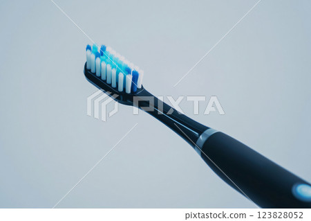 Sleek black and blue electric toothbrush with soft bristles, isolated on a white background, perfect for dental hygiene concepts 123828052