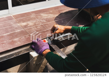 Male worker measuring iron with metal ruler in building site. 123828124