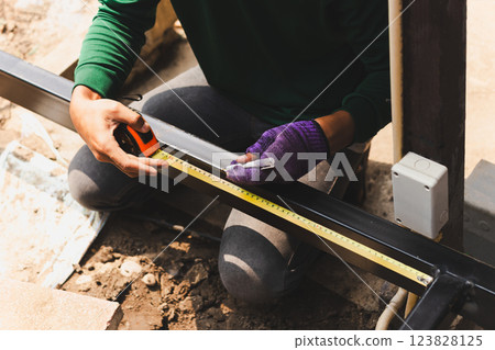 Ironworker measuring with hand holding a pen in building site. Ironworker measuring with hand holding a pen in building site. 123828125