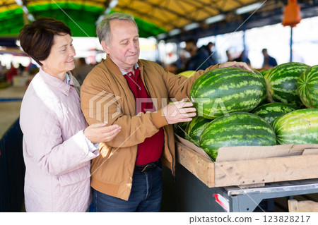 Man and woman customers buying watermelon in open-air market Man and woman customers buying watermelon in open-air market 123828217