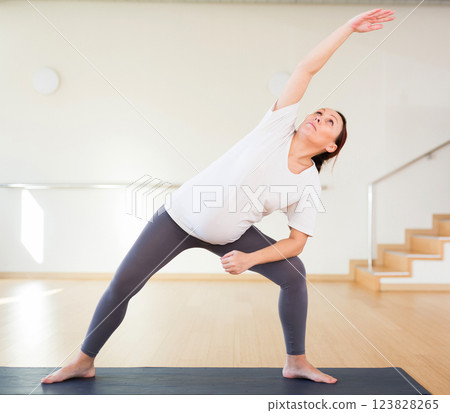 Pregnant woman is engaged in yoga. Extended Side Angle Pose or Utthita Parsvakonasana Pregnant woman is engaged in yoga. Extended Side Angle Pose or Utthita Parsvakonasana 123828265