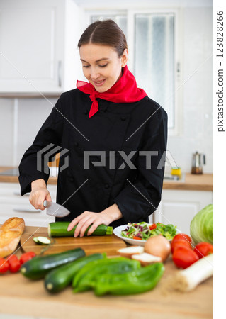 Female cook in black uniform chopping vegetables in kitchen 123828266