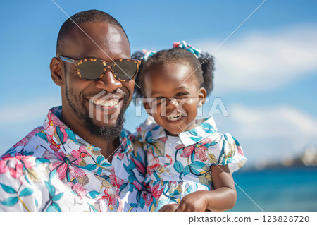 Tourist is holding his daughter while smiling on a beach. They are both wearing matching outfits and enjoying their vacation 123828720