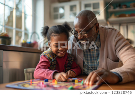 Grandfather and his granddaughter are spending quality time together, playing a board game at home. They are both smiling and having fun 123828746