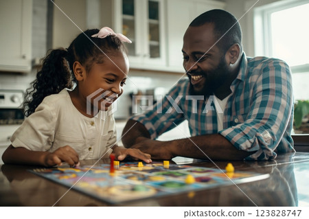 Father and daughter are laughing and enjoying their time together while playing a board game at their kitchen table 123828747