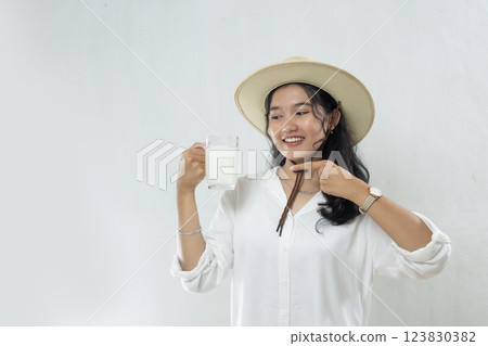 very young woman in white coat and casual hat holding a glass of milk smiling while pointing at the milk, advertisement of healthy living woman drinking milk very young woman in white coat and casual hat holding a glass of milk smiling while pointing at the milk, advertisement of healthy living woman drinking milk 123830382