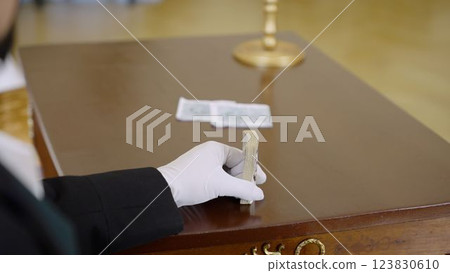 17th century ball, man with playing cards. A nobleman in the image with a deck of cards in his hands. A hand in a white glove holds a deck of cards, close-up. 123830610