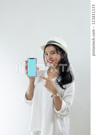 portrait of Young Asian woman wearing straw hat, all white clothes and holding her smartphone while appearing for holiday trip, travel advertisement portrait of Young Asian woman wearing straw hat, all white clothes and holding her smartphone while appearing for holiday trip, travel advertisement 123831133