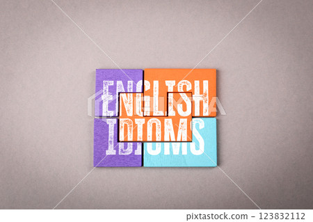 English Idioms. Colorful wooden puzzle pieces on a gray background 123832112