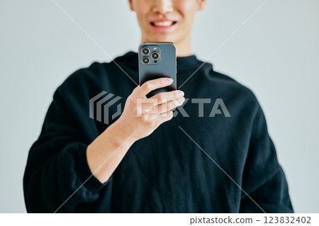 一名20多歲的年輕人正在操作智慧型手機 123832402