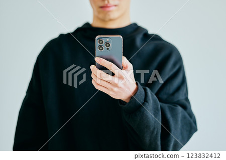 A young man in his twenties operating a smartphone 123832412