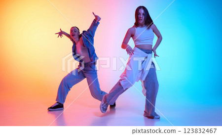 Electrifying hip hop performance by two dancers in urban fashion against neon gradient backdrop. Electrifying hip hop performance by two dancers in urban fashion against neon gradient backdrop. 123832467