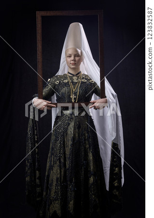 Portrait of noblewoman in renaissance attire holding wooden frame, standing with poised expression, creating illusion of self-portrait against dark background. Portrait of noblewoman in renaissance attire holding wooden frame, standing with poised expression, creating illusion of self-portrait against dark background. 123832587