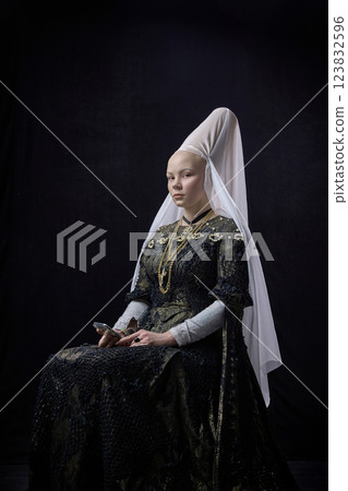 Portrait of young noblewoman in renaissance attire holding smartphone, gazing forward with composed expression against dark vintage background. Portrait of young noblewoman in renaissance attire holding smartphone, gazing forward with composed expression against dark vintage background. 123832596