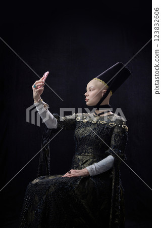 Medieval woman dressed elegant, renaissance style clothes making selfie using modern smartphone against dark vintage background. Medieval woman dressed elegant, renaissance style clothes making selfie using modern smartphone against dark vintage background. 123832606