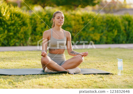 A Young Woman Engaged in Meditation Practices Outdoors Surrounded by a Serene Environment A Young Woman Engaged in Meditation Practices Outdoors Surrounded by a Serene Environment 123832646