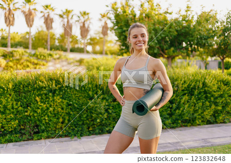 A Fit Young Woman Holding a Yoga Mat Enjoying an Outdoor Setting Surrounded by Nature A Fit Young Woman Holding a Yoga Mat Enjoying an Outdoor Setting Surrounded by Nature 123832648