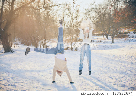 Joyful friends, man and woman, dressed warm winter sweaters, throwing snow at each other, sharing laughter in winter park. Joyful friends, man and woman, dressed warm winter sweaters, throwing snow at each other, sharing laughter in winter park. 123832674