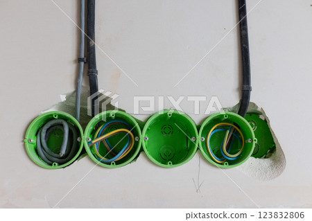 Green electric sockets box in the wall. Electric outlet installation. Closeup. 123832806