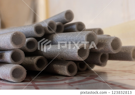 Grey soft isolation for pipes of the water supply and heating system. Closeup, selective focus. 123832813