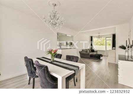 A bright and stylish interior featuring a modern dining table, plush black chairs, and a cozy living area with large windows, perfect for contemporary living. A bright and stylish interior featuring a modern dining table, plush black chairs, and a cozy living area with large windows, perfect for contemporary living. 123832932