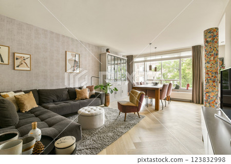 A beautifully designed modern living room showcasing elegant furniture, artistic decor, and ample natural light flowing through large windows. A beautifully designed modern living room showcasing elegant furniture, artistic decor, and ample natural light flowing through large windows. 123832998