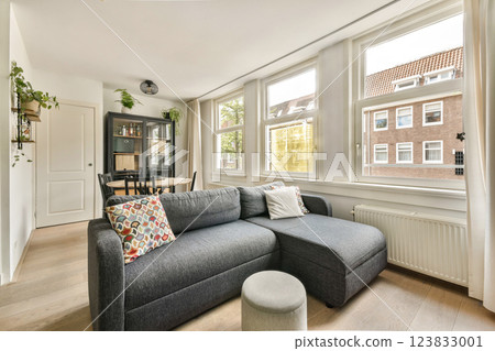 A stylish modern living room featuring a comfortable sectional sofa, natural light from large windows, and contemporary decor that enhances the cozy atmosphere. 123833001