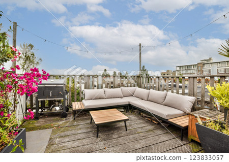A beautifully designed rooftop lounge featuring comfy seating, modern tables, and vibrant flowers, perfect for relaxation in a serene urban environment. 123833057