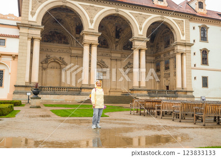 A female tourist walks around along a decorative alley decorated with many statues in a decorative park at Wallenstein Palace building in Prague in Czech Republic 123833133