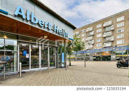 A vibrant urban landscape featuring the storefront of an Albert Heijn grocery store amidst residential buildings, capturing everyday life in the city. A vibrant urban landscape featuring the storefront of an Albert Heijn grocery store amidst residential buildings, capturing everyday life in the city. 123833194