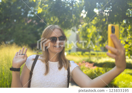 Cheerful smiling 30s lady taking selfie outdoors in city park, happy young female capturing self-portrait while enjoying walk and good day, resting outside Cheerful smiling 30s lady taking selfie outdoors in city park, happy young female capturing self-portrait while enjoying walk and good day, resting outside 123833195