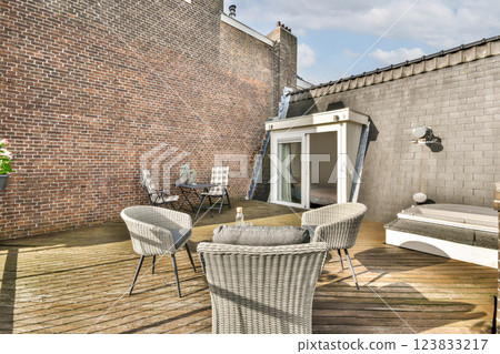 A stylish outdoor patio featuring modern furniture, wooden decking, and a brick wall backdrop, perfect for relaxation and gatherings. A stylish outdoor patio featuring modern furniture, wooden decking, and a brick wall backdrop, perfect for relaxation and gatherings. 123833217